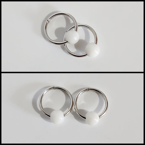 Deux images des Boucles d'oreilles Dormeuses de la joaillerie fine MONA illustrent l'élégance. L'image du haut montre les anneaux circulaires en argent avec des perles blanches qui se chevauchent, tandis que l'image du bas présente ces boucles d'oreilles exquises côte à côte sur un fond blanc immaculé.