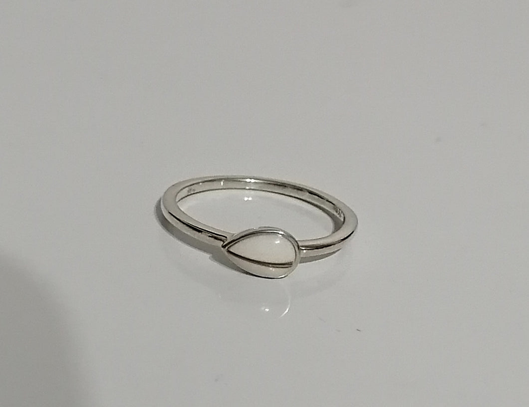 Une bague solitaire MONA fine joaillerie Bague Goutte de vie dotée d'un anneau simple et élégant et d'une unique monture ovale à inclusions, soulignée sur un fond blanc uni.