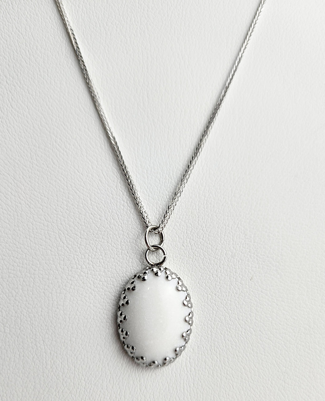 Élégant collier en acier inoxydable avec un simple pendentif ovale Pendentif Griffes sur fond texturé par Bijoux La Précieuse.