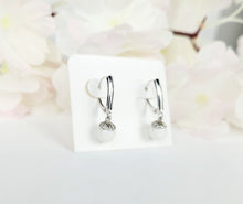 Load image into Gallery viewer, Une paire d&#39;élégantes boucles d&#39;oreilles en argent avec des gouttes de perles bijou, présentées sur un support blanc sur un fond flou de fleurs rose pâle. Boucles d&#39;oreilles Fermoirs de la Bijouterie Langlois.
