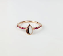 Charger l&#39;image dans la galerie, La Bague Goutte de vie vers le haut (avec zircons) de MONA fine joaillerie est ornée d&#39;une pierre blanche en forme de larme au centre et de petits zircons rouges le long de la bande, sur fond blanc.
