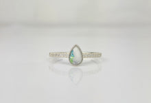 Charger l&#39;image dans la galerie, La Bague Goutte de vie vers le haut (avec zircons) de MONA fine joaillerie se compose d&#39;une pierre précieuse en forme de goutte aux teintes bleu-vert et d&#39;une bande d&#39;argent sertie de petits zircons, élégamment présentés sur une surface blanche réfléchissante.
