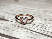 Charger l&#39;image dans la galerie, La MONA fine joaillerie Bague Coeur avec zircons présente une pierre blanche en forme de cœur encadrée de zircons étincelants, présentée sur du bois texturé pour un look anneau élégant et minimaliste.
