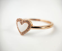 Charger l&#39;image dans la galerie, La Bague Coeur avec zircons de MONA fine joaillerie présente un centre blanc en forme de cœur, rehaussé de zircons étincelants, et se détache sur un fond blanc.
