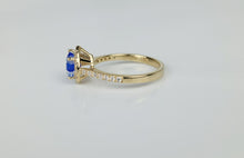 Load image into Gallery viewer, La Bague Bonheur Éternel de la Bijouterie Langlois est une bague en or ornée d&#39;une pierre centrale bleue en forme de goutte, entourée de pierres transparentes plus petites disposées le long de l&#39;anneau. Le fond est une surface blanche unie, mettant en valeur les détails complexes et l&#39;élégance de ce design en or 10 carats.
