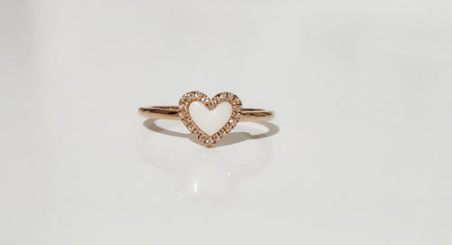 La Bague Coeur avec zircons de MONA fine joaillerie est une anneau minimaliste en or, ornée d'un cœur blanc central entouré de zircons scintillants, présentée sur un fond blanc épuré.