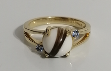 Charger l&#39;image dans la galerie, Une Bague Angélique de joaillerie fine MONA en or brillant avec une pièce maîtresse distinctive en forme de cœur de pierres précieuses brunes et blanches, flanquée de deux petites pierres bleues scintillantes.
