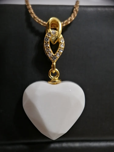 Un pendentif Shawna de Bijoux La Précieuse avec une bélière incrustée de zircons scintillants est délicatement suspendu sur un fond sombre, symbolisant l'élégance et l'affection.