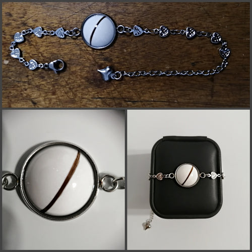 Un collage de trois images présentant un bracelet chaîne en coeur de Bijoux La Précieuse, avec un pendentif rond blanc comportant une seule bande marron, complété par des motifs de maillons complexes et une petite breloque, présentés tous deux librement.