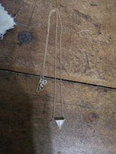 Charger l&#39;image dans la galerie, Un délicat collier Collier Triangle fin MONA joaillerie avec un pendentif triangulaire comportant des inclusions personnalisées sur une surface en bois.

