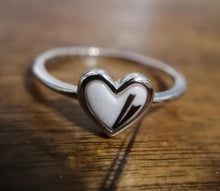 Load image into Gallery viewer, Une Bague Coeur en argent avec un anneau mince et un cœur central, reposant sur une surface en bois, symbolisant l&#39;amour et l&#39;affection de la MONA fine joaillerie.
