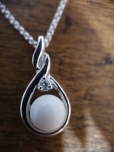 Un délicat collier en argent avec un Pendentif Amiko en forme de larme comportant en son centre un petit zircon rond blanc de couleur diamant et un minuscule embellissement qui ressemble à la Bijouterie Langlois.