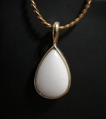 Élégant Pendentif Goutte15 blanc en forme de larme sur un collier doré de MONA fine joaillerie sur fond noir.