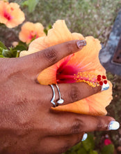 Load image into Gallery viewer, Une main au nail art scintillant touchant doucement les pétales d&#39;une fleur d&#39;hibiscus orange vif, mettant en valeur une bague MONA fine joaillerie Bague Maëva à l&#39;annulaire.
